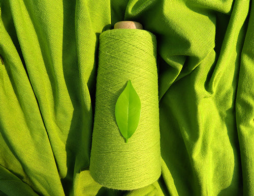 Image of green thread on green fabric background with leaf